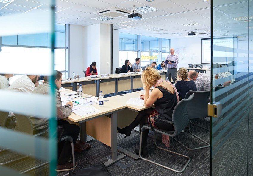 Wide shot of a project management course, where the instructor refers to a textbook