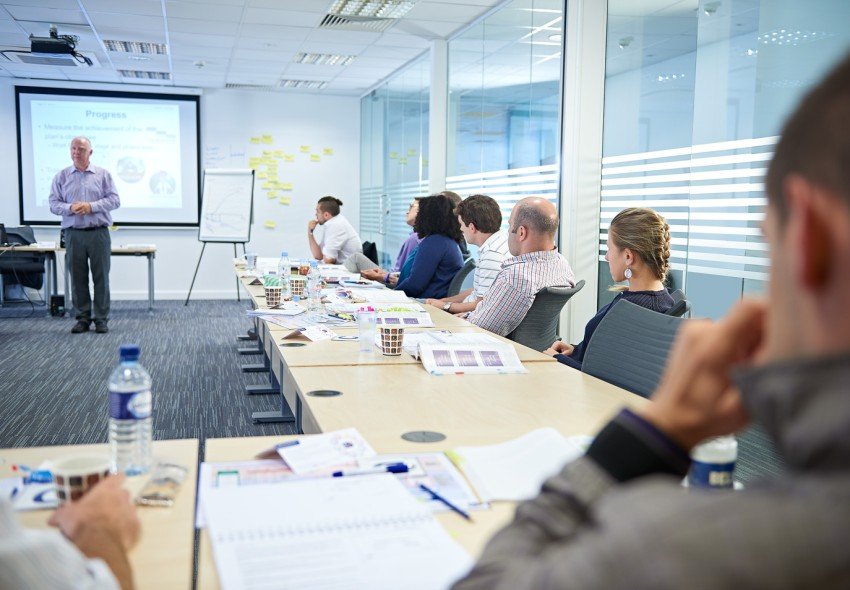 Project management instructor teaching a classroom in front of a slideshow.