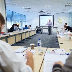 Delegates taking notes in front of a course instructor. - Thumbnail