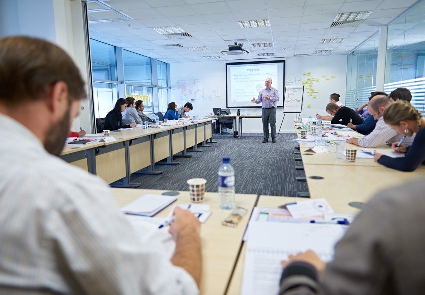 Delegates taking notes in front of a course instructor.