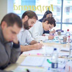 Project management course delegates with their heads down, taking notes - Thumbnail